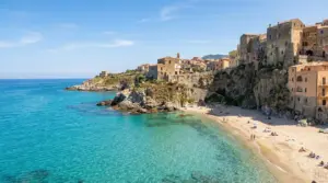 Spiaggia con mare turchese e case antiche su una scogliera in una località italiana