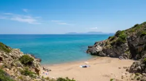 Spiaggia tranquilla con sabbia dorata e mare turchese circondata da scogli e natura